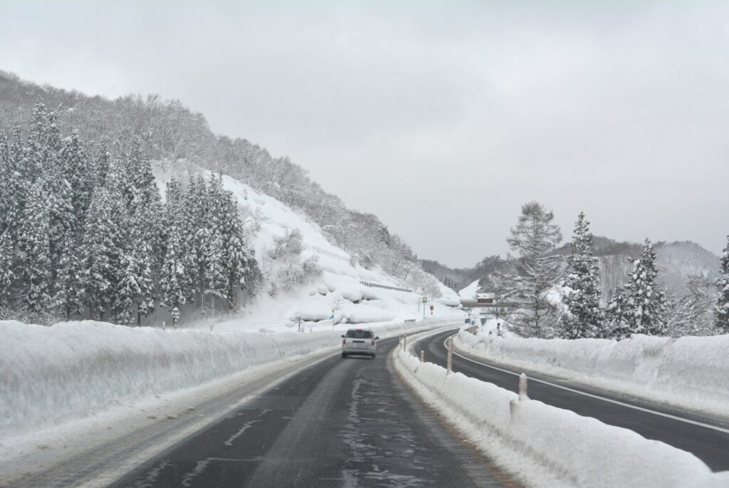 雪道・路面凍結の道を運転する車